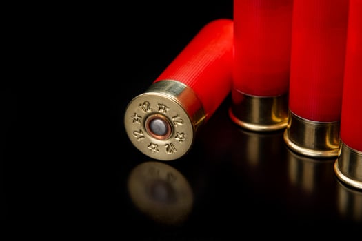 Shotgun shells on a black reflective surface. Ammunition for 12 gauge smoothbore weapons. Hunting ammunition. Dark back. photo
