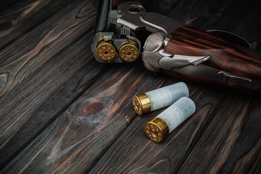 Classic trigger double-barreled hunting rifle on a wooden background. Concept postcards for hunters. Smooth-bore hunting rifle open for reloading. photo