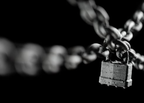 Worn rusted chain and pad lock on black background. Conceptual strength, protection, or security system. Shallow DOF. photo