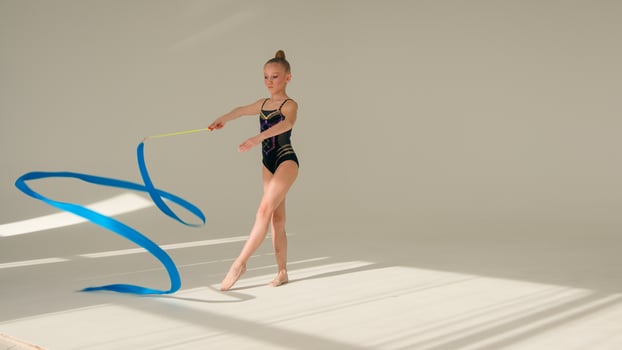Talented Caucasian little girl child kid daughter gymnast dancer sport ballerina athlete perform acrobatic exercise spinning gymnastic ribbon artistic element in white studio dance class ballet school photo