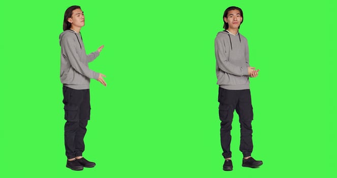 Male person creating advertisement and showing something to left or right sides on camera, pointing at thing over full body greenscreen. Young adult advertising slogan for marketing commercial. photo