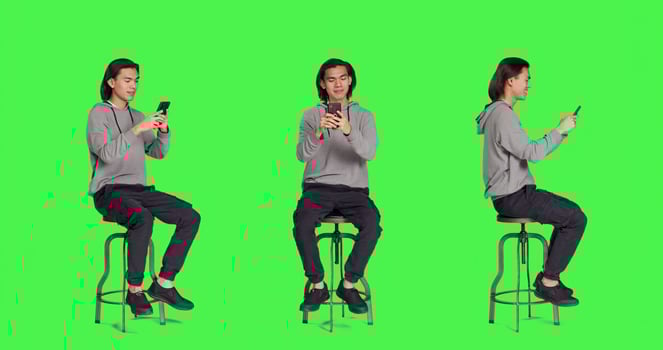 Adult typing text messages on phone while sitting on chair, browsing social media app for messaging on smartphone. Young trendy person using device to communicate with people. photo