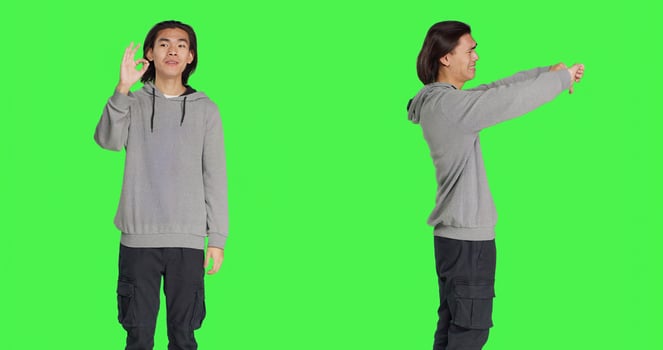 Person doing okay sign and showing disapproval at the same time, expressing positivity and negativity over greenscreen isolated backdrop. Young man presenting good and bad sign. photo