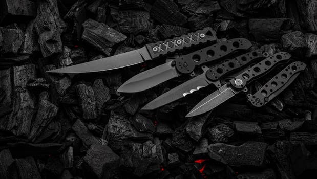 Modern knives with black blades. Hunting, military and folding knives on smoldering charcoal. Black back. photo