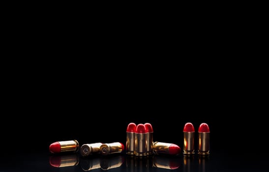 Pistol cartridges with red silicone coating. Bullets for a pistol on a dark back. Reflections on a black surface. photo