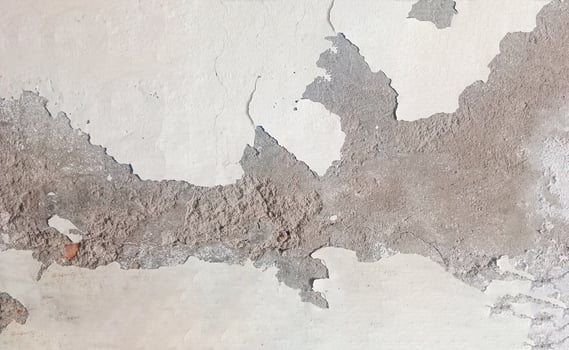 Weathered Wall Texture with Peeling Paint revealing the underlying concrete or plaster. The surface is uneven and shows signs of wear and tear, with cracks, chips, and exposed patches photo
