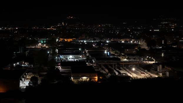 A serene night over the bustling industrial district illuminated by city lights and distant hills photo