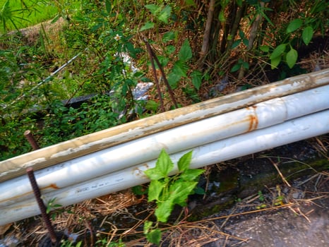 A pile of long PVC pipes lying in the garden. photo