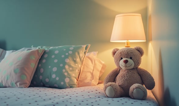 Plush bear sitting upright on bed, polka dot pillows photo