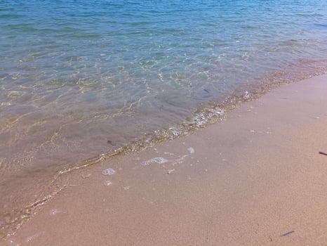 Soft blue ocean wave on fine sandy beach background photo