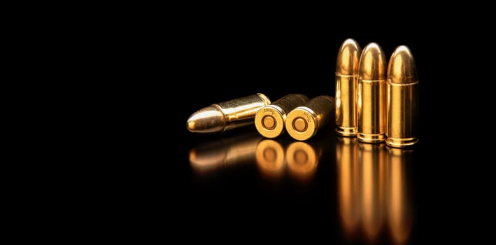 Pistol cartridges 9 mm on a smooth glossy surface with reflections. Ammunition for pistols and PCC carbines on a dark back. photo