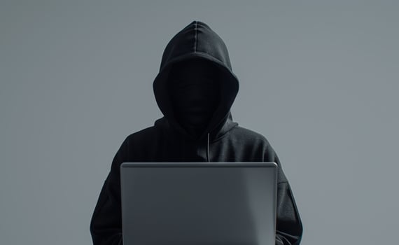 Anonymous Hooded Figure Using Laptop for Cybersecurity or Hacking in Dark Environment photo