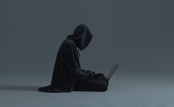 Mysterious Figure in Black Hoodie Using Laptop in Dark Environment photo