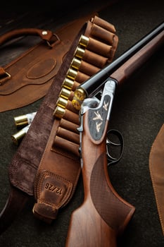 Classic trigger double-barreled hunting rifle on a green background. Smooth-bore hunting rifle open for reloading. Concept postcards for hunters. photo