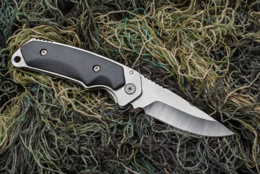 Folding penknife on the background of green threads. photo