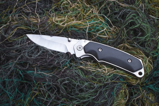 Folding penknife on the background of green threads. photo