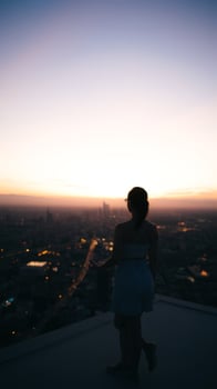 Woman Silhouette on Rooftop with City Lights in Background photo