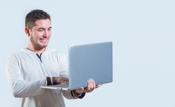 Excited guy holding and looking at an promotion on laptop screen. Portrait of happy young man standing using laptop isolated photo