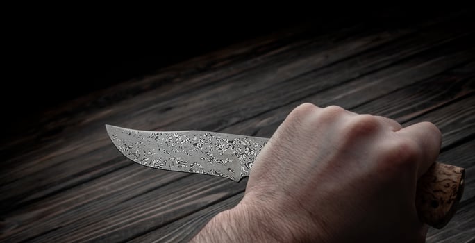 Hunting bowie knife with a wooden handle on dark wooden background. Steel arms weapon. top view photo