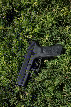 Modern semi-automatic pistol. Armament for the army and police. Short-barreled weapon. Green fir background. photo