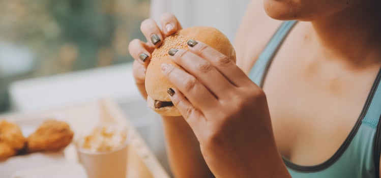 Binge eating disorder concept with woman eating fast food burger, fired chicken , donuts and desserts photo