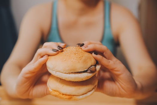 Binge eating disorder concept with woman eating fast food burger, fired chicken , donuts and desserts photo