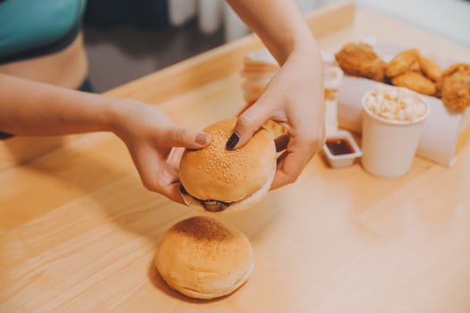 Binge eating disorder concept with woman eating fast food burger, fired chicken , donuts and desserts photo