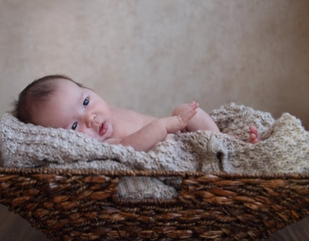 Baby boy in the basket on the wooden floor photo