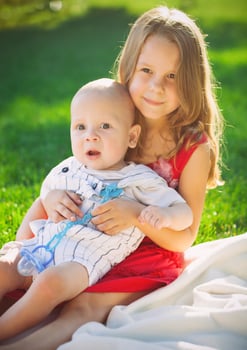 Two children baby brother and sister on green meadow photo