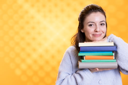 Portrait of happy woman holding pile of books, portraying reading blissfulness concept, studio background. Cheerful book lover hugging stack of novels, showing appreciation for literature photo