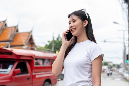 A beautiful Asian woman is talking on the phone while standing by the street in the city. photo