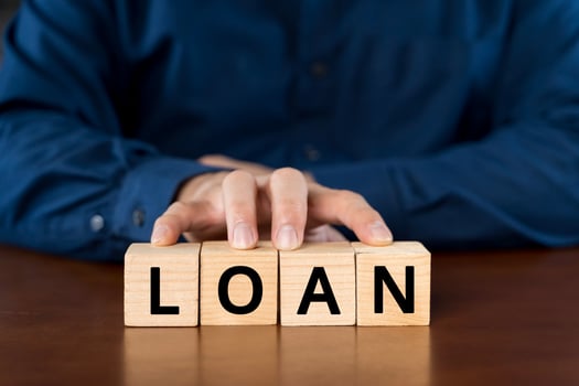 Businessman presses wooden blocks with the word loan photo