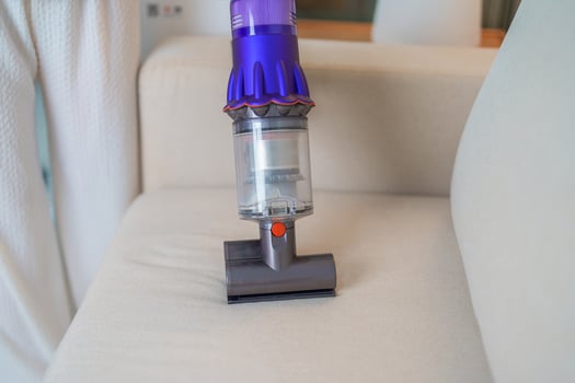 Woman cleaning Sofa with cordless Vacuum cleaner. Housewife using wireless Vacuum for big cleaning home. Housework, Housecleaning, Housekeeping, Removes dust, Domestic hygiene and daily routine photo
