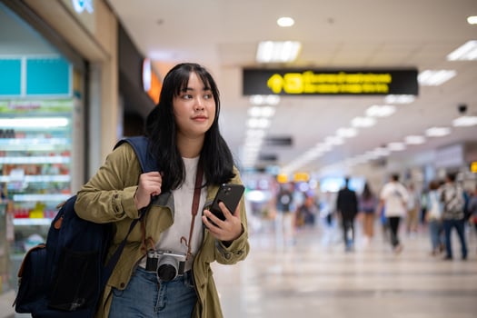 A female solo traveler or backpacker is walking in the airport, looking for her check-in counter. photo