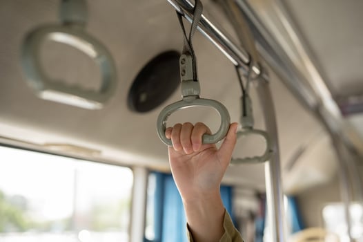 A close-up image of a woman hand holding a bus hanger while standing on a public bus. photo