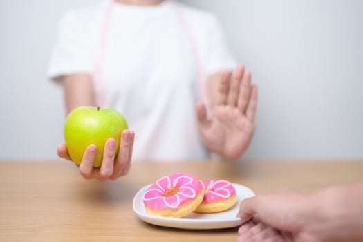 woman hand hold green Apple and reject donut, female fitness choose between fruit is Healthy and sweet is Unhealthy junk food. Dieting control, Weight loss, Obesity, eating lifestyle and nutrition photo