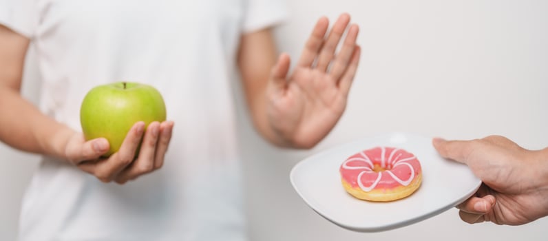 woman hand hold green Apple and reject donut, female fitness choose between fruit is Healthy and sweet is Unhealthy junk food. Dieting control, Weight loss, Obesity, eating lifestyle and nutrition photo