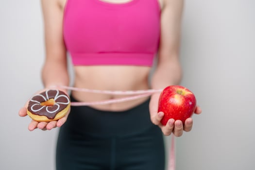 woman hand hold red Apple and donut, female fitness choose between fruit is Healthy and sweet is Unhealthy junk food. Dieting control, Weight loss, Obesity, eating lifestyle and nutrition concept photo