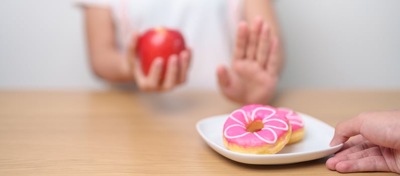 woman hand hold red Apple and reject donut, female fitness choose between fruit is Healthy and sweet is Unhealthy junk food. Dieting control, Weight loss, Obesity, eating lifestyle and nutrition photo