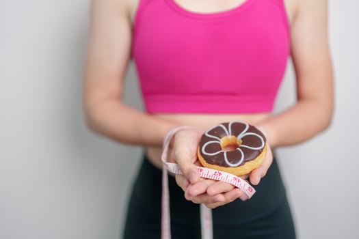 woman hand hold Donut with tape measure, choose stop eating sweet is Unhealthy ealthy food. Dieting control, Weight loss, Obesity, eating lifestyle and nutrition concepts photo
