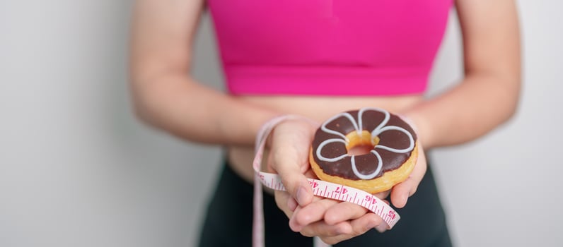 woman hand hold Donut with tape measure, choose stop eating sweet is Unhealthy ealthy food. Dieting control, Weight loss, Obesity, eating lifestyle and nutrition concepts photo