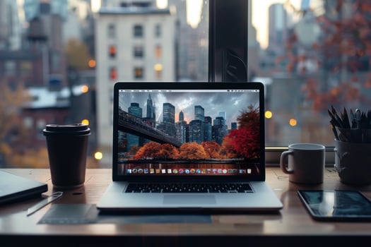 Cozy workspace with a laptop displaying a city skyline at sunset and autumn foliage in a New York setting photo
