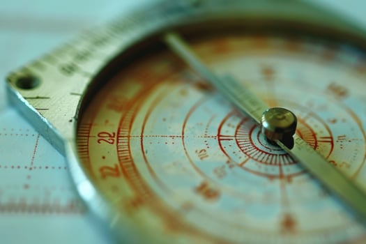 Close-up of a vintage compass on a map, showcasing intricate details and markings during daylight photo
