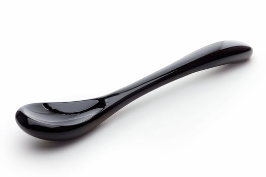 Elegant black ceramic spoon resting on a smooth surface, showcasing its sleek design and unique shape in bright light photo