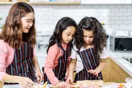 Group of three Diverse Family, Asian and Arab Preschool kid person make Cake cooking in kitchen, Mother teaching small cute daughter prepare decoration pretty with fun, Cream mess over face photo