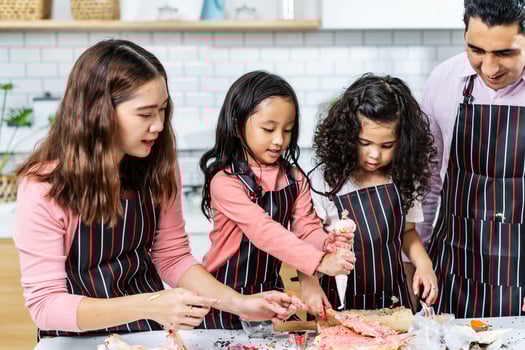 Group of four Diverse Family, Asian and Arab Preschool kid person make Cake cooking in kitchen, Father Mother teaching small cute daughter prepare decoration pretty with fun, Cream mess over face photo