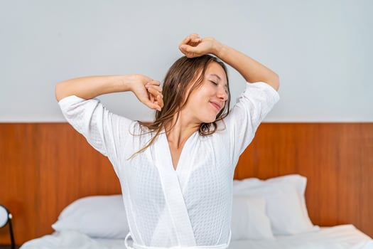 Caucasian beautiful girl in pajamas wake up in the morning with happiness. Attractive young woman smiling, feel happy and relax then stretching body after getting up from sleep on bed in bedroom photo