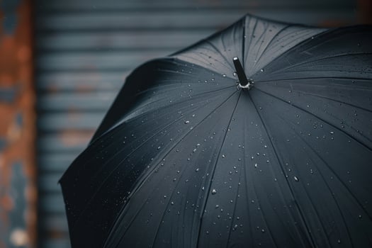 Black umbrella with raindrops standing against a weathered background on a rainy day photo
