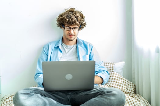 work from home. young caucasian man working on computer laptop. study online listening learning education course conference calling sit laying down on bed elearning concept, freelancer at home photo