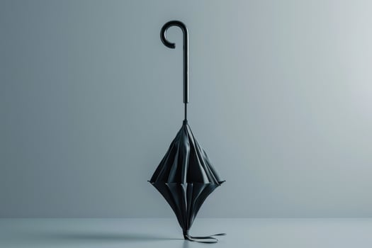 Black umbrella standing upright on a smooth surface against a pale background in a minimalist setting photo